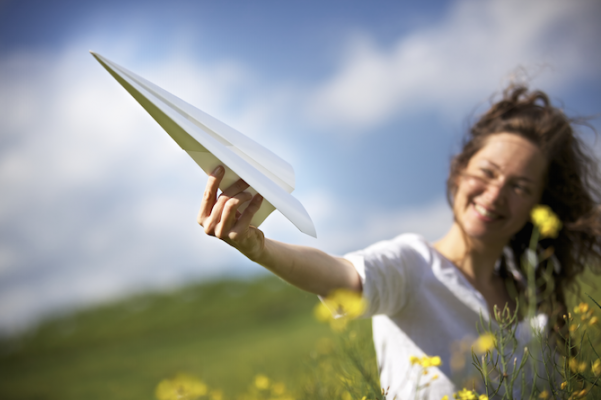 vrouw in veld met papieren vliegtuigje