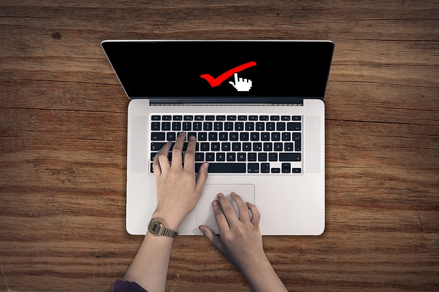 laptop met handen op toetsenbord en rood vinkje op het scherm