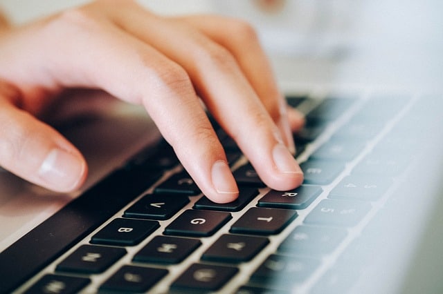 Hand op laptop toetsenbord op pagina over online tekstschrijver